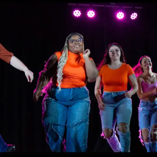 Ivana and members of the Widener Dance Company perform wearing blue jeans and orange tops
