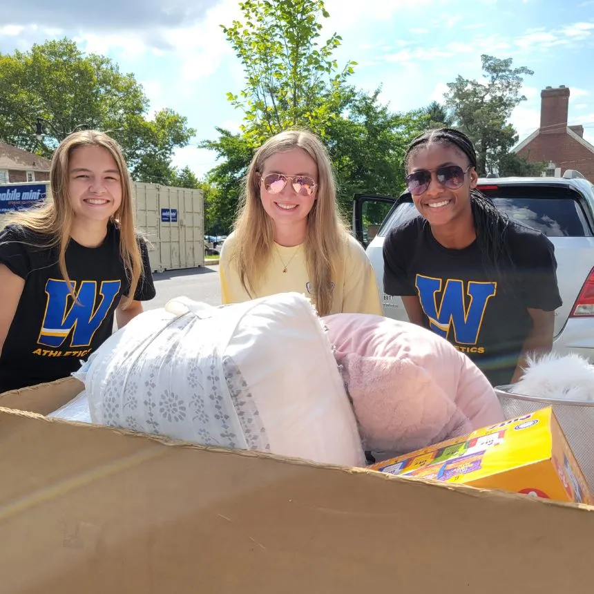 Two female student volunteers smile with an incoming student.