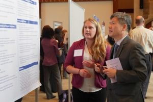 Student discussing poster presentation with faculty member during graduate research symposium