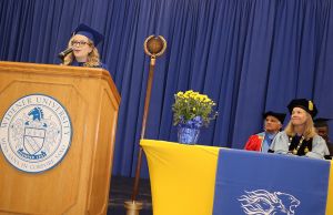 Megan Sharp delivers her remarks at the podium while faculty watch during academic convocation.