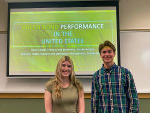 Shealyn Hubbs and Daniel Wiedl stand in front of a screen with a green slide on green bond performance