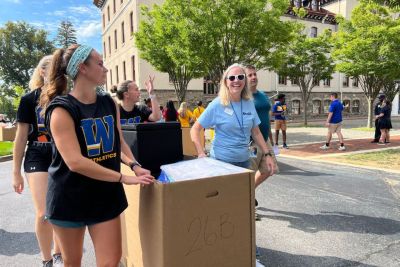 President Robertson and students pushing a move-in cart through the parking lot