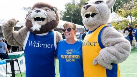Woman with blonde hair wearing blue Widener University T-shirt, surrounded by two lion mascots.