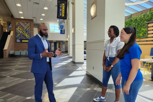Fred McCall standing and speaking with two students in the University Center atrium