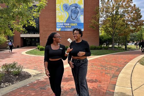Two sibling students on campus talking with each other.