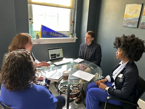 Three administrators and the (student) president for a day seated at a circular table in admissions.